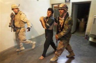 A U.S. Marine, left, and an Iraqi soldier lead a man through his house during a raid in Saadah, Iraq, eight miles from the border with Syria, Wednesday, Nov. 30, 2005.