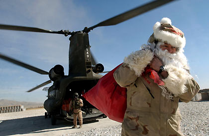 aptain Clace Perzel, dressed as Santa Claus, he carries a bag of gifts for distribution at his base to mark Christmas at the U.S. base in Ghazni province, west of Kabul, December 24, 2005. 