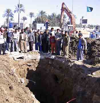 Iraqi residents view a hole in which human bones were found in Kerbala, 270 km (160 miles) south of Baghdad, December 27, 2005.