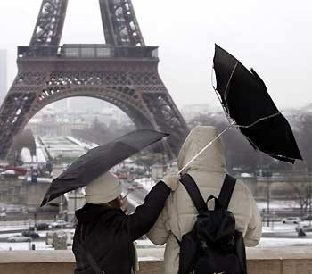 Tourists fight against a gust of wind as they stand near the Eiffel Tower in Paris December 30, 2005. Cold weather conditions have prevailed in France since the beginning of the week with snowfall and icy conditions in many parts of the country. 