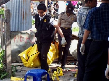 Police officers carry a body bag containing the body of a bombing victim at a market in Palu, central Sulawesi, Indonesia, Saturday, Dec. 31, 2005.
