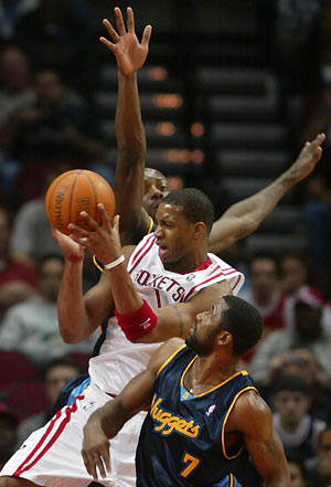 Houston Rockets forward Tracy McGrady (C) catches the ball as he is defended by Denver Nuggets center Francisco Elson and guard Greg Buckner (7) in the first half of NBA action at the Toyota Center in Houston January 8, 2006. [Reuters]