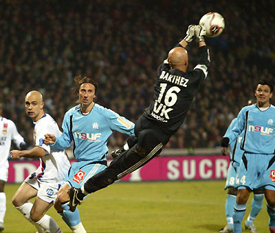 Olympique Marseille goalkeeper Fabien Barthez (C) reaches for the ball in front of team mate Frederic Dehu and Olympique Lyon's Cris (L) during their French Ligue 1 soccer match at the Gerland stadium in Lyon January 11, 2006. [Reuters]