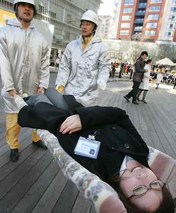 A Japanese office worker is carried on an improvised stretcher made out of blankets and poles during an earthquake disaster drill in Tokyo January 17, 2006. 