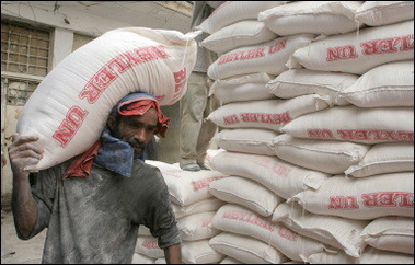 An Iraqi worker carries bags of government wheat rations in the Shiite Baghdad suburb of Sadr City. 