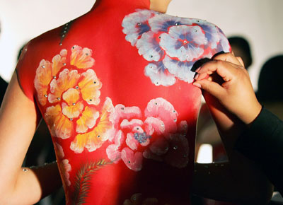 A makeup artist applies sequins to the made-up skin of a model painted in the style of the Chinese Qi Pao dress at a Chinese New Year celebration MAC fashion show in New York February 2, 2006. The elaborate makeup applications took up to eight hours to apply on the topless models who then posed in front of backdrops at a cocktail party. The show kicks off Fashion Week which starts on Friday.