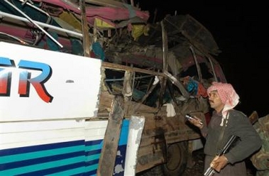 An unidentfied Pakistani police officer looks at passenger bus damaged by a bomb explosion, Sunday, Feb 5, 2006 in Kolpur, about 18 kilometer southeast of Quetta, Pakistan. 