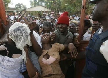 A woman struggles as people force their way past a gate at a polling station while trying to cast their vote during primary elections in the town of Marmelade, Haiti on Tuesday Feb. 7, 2006.(