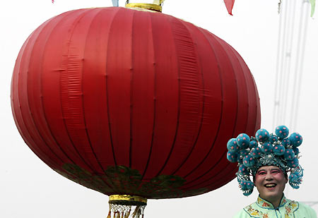 A Chinese performer dances beside a giant red lantern during a Lantern Festival activity in Beijing February 12, 2006. Lantern Festival marks the last day of the 15-day long Spring Festival, the most important festival of the year in China. [Reuters]