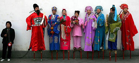 Chinese performers rest on stilts during celebrations for Lantern Festival at the Longhua temple fair in Shanghai February 12, 2006. Chinese worshippers visited the ancient temple to usher in the Year of the Dog. Lantern Festival marks the last day of the 15-day Spring Festival in China. 