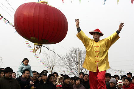 A Chinese performer dances beside a giant red lantern during a Lantern Festival activity in Beijing February 12, 2006. Lantern Festival marks the last day of the 15-day long Spring Festival, the most important festival of the year in China. [Reuters]