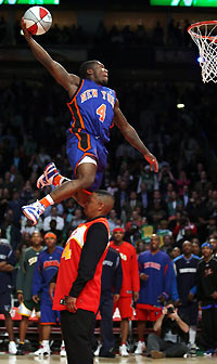 New York Knicks guard Nate Robinson skies over 1986 slam dunk champion Spud Webb during the slam dunk contest at the 2006 NBA All-Star Weekend in Houston, Texas, February 18, 2006. Robinson won the event. 