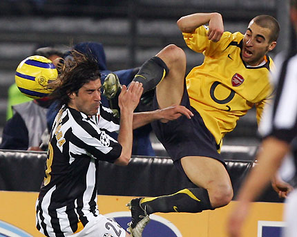 Giuliano Giannichedda (L) challenges Mathieu Flamini of Arsenal during the second leg of their Champions League quarter-final soccer match 