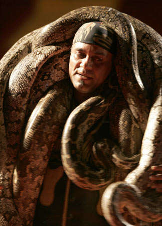 An Iranian acrobat from the Tehran Great Circus carries snakes as he performs during a show in Tehran July 4, 2006. 