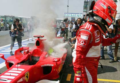 German Formula One driver Michael Schumacher looks back at his Ferrari after it caught fire during the third practice session of the French Grand Prix at the Magny-Cours circuit July 15, 2006.