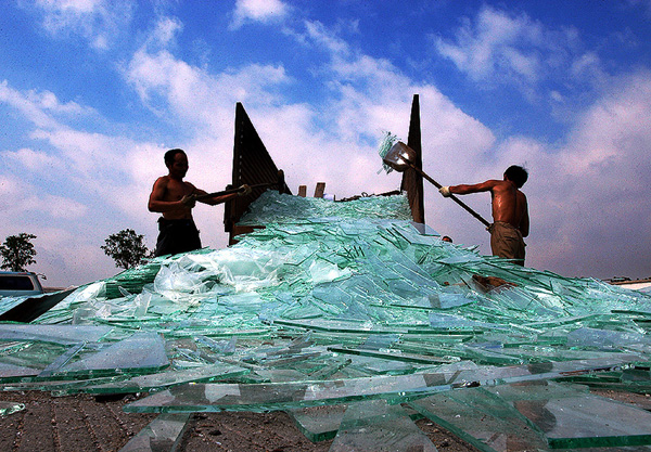 Two workers clean the broken glass off a road in Foshan, South China's Guangdong Province May 13 2005. 