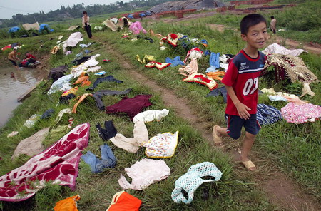 A boy walks amid scattered clothes on a field in Nanjing, East China's Jiangsu Province, August 7, 2006. Local residents aired the clothes out after a heavy rain during a hurricane. [Shi Xianghui/Modern Express]