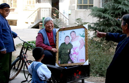  Ping Zhanxiang (L), 83, and his wife Li Aimin (2nd L), 78, show their wedding photo at a community in Shijiazhuang, North China's Hebei Province, October 29, 2006. Local authorities organized 99 couples who have been married over fifty years to have their photos taken. [Yan Zhiguo/Yanzhao Evening News]