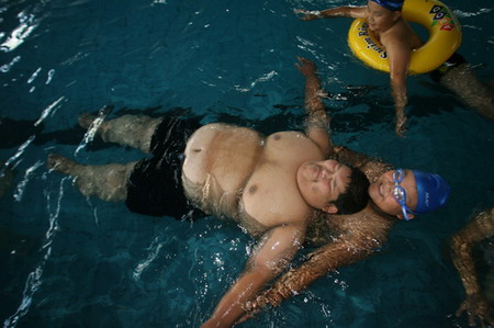 Zhu Lei (L) floats in a swimming pool with the help of an unidentified man in Changchun, Northeast China's Liaoning Province, December 21, 2006. Zhu Lei weighted 217 kilograms and 