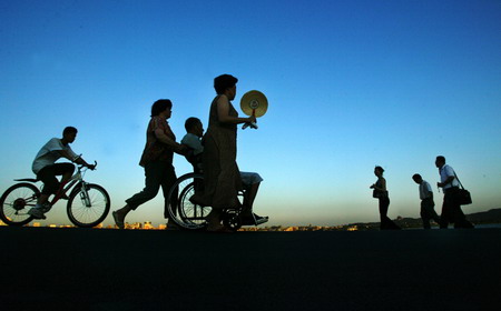 People pass a street at sunset in Hangzhou, East China's Zhejaing Province, July 28, 2006. [Dai Shulin/Metro Express]