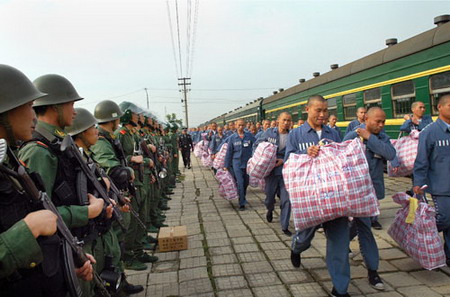 Soldiers stand guard as prisoners leave a train that transferred them from the prisons in Zhejiang Province to Anhui Province at a railway station in Hefei, East China's Anhui Province, May 14, 2006. [Min Yan/ Xin'an Evening News]