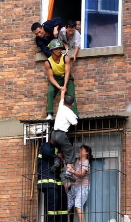 Firemen rescue a man in white T-shirt from a building in Nanchang, East China's Jiangxi Province, August 27th, 2006. The drunken man threatened to jump to his death from the building after failing to get money from his parents. [Ouyang Sumin/Jiang'nan Metropolitan News]