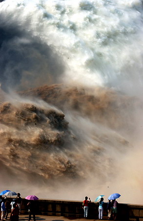 Visitors look at the water gushing from the Xiaolangdi Reservoir on the Yellow River in Central China's Henan Province, June 27, 2006. About 3,000 cubic meters per second of water was discharged out of the reservoir for 15 days to wash the sand from the riverbed into the sea. [Li Kang/Dahe Newspaper]