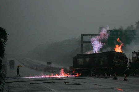 Fire burns mark a truck carrying methyl alcohol after it collided with a truck carrying wood on a road in Guangzhou, South China's Guangdong Province, June 3, 2006. [Yan Ming/Southern Metropolitan News]