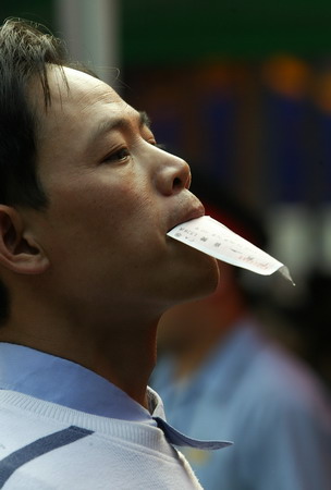 A passenger holds a ticket in his mouth before boarding a train at a railway station in Guangzhou, South China's Guangdong Province, January 16, 2006.[Wang Xiaoming/New Express]