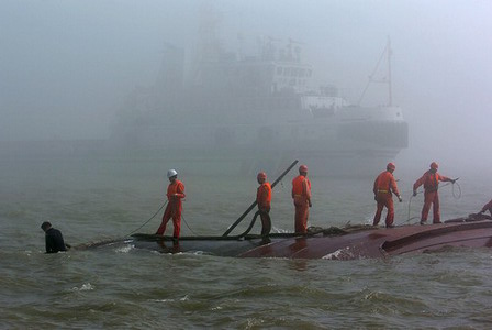 Rescuers stand on a capsized fishing boat in Qiongzhou Straight in South China's Hainan Province, January 17, 2006. The accident left six people missing. [Li Xiaogang/Southland Metropolis Daily]