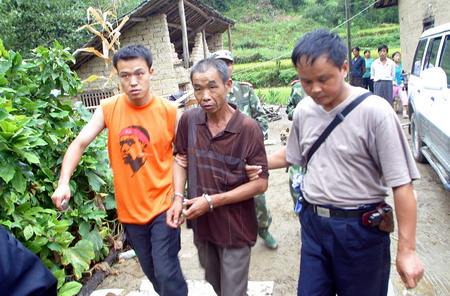 Law enforcement workers escort Qiu Xinghua (center) in Foping County, North China's Shannxi Province, August 20, 2006. Qiu killed ten people in a temple near his home, because he thought one of the victims had flirted with his wife, which was found to be not true. Qiu was sentenced to death in October and executed on December 28,2006. [Dong Xiaoming/Huashang News]