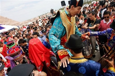 The world's tallest man, Bao Xishun, who stands 2.36 metres (7 feet 9 inches), and his bride (in red veil at left) are surrounded by guests at their public wedding ceremony at the tomb of Kublai Khan on the outskirts of Erdos, in China's northern Inner Mongolia Autonomous Region, Thursday, July 12, 2007. Bao married 1.68-meter-tall Xia Shujuan, who is half the groom's age at 28, after conducting a worldwide search for a bride. Xia is from Bao's hometown of Chifeng in northern China. [AP]