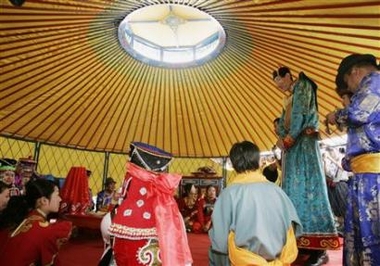 Bao Xishun (2nd R), 56, a 2.36-metre (7 ft, 9 inches) herdsman listed by the Guinness World Records as the tallest living man, walks into a yurt and meets his bride Xia Shujuan (covered L), 29, 1.68 metres (5 ft., 5 inches), during their wedding ceremony at Genghis Khan's Mausoleum on the outskirts of Erdos in north China's Inner Mongolia Autonomous Region July 12, 2007. [Reuters]