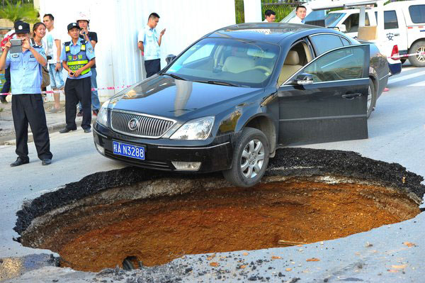 Sinkhole blocks road, damages 2 cars