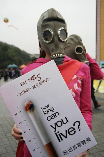 Mask-wearing radio hostesses hold anti-smoking posters in Hangzhou