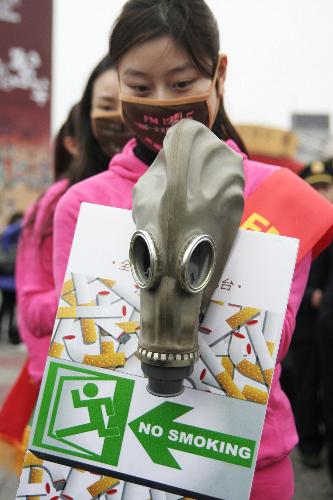 Mask-wearing radio hostesses hold anti-smoking posters in Hangzhou