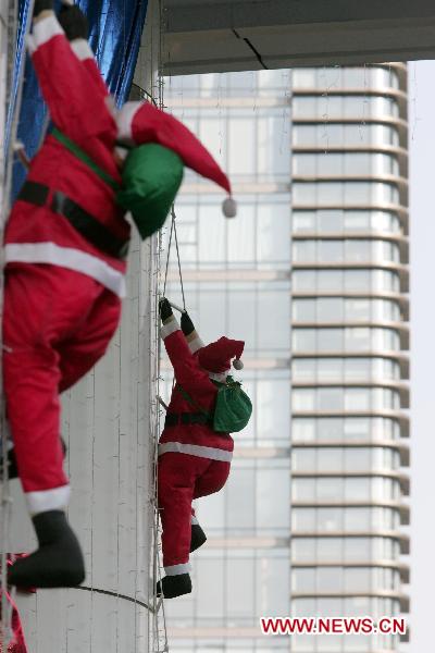 Santa Clauses cling to skyscraper in Hangzhou before Christmas