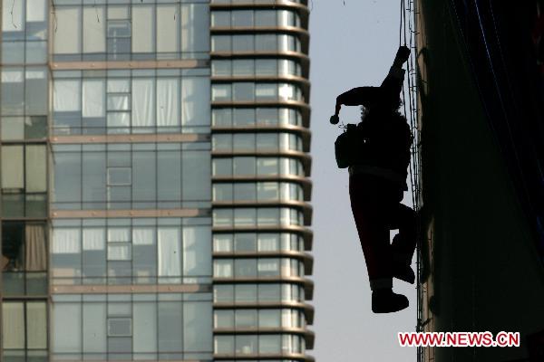 Santa Clauses cling to skyscraper in Hangzhou before Christmas