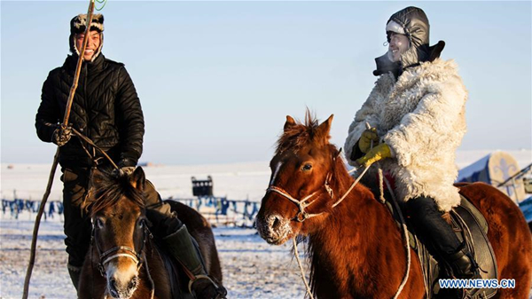 Herdsmen graze horses on snow-covered pasture of Hulunbuir