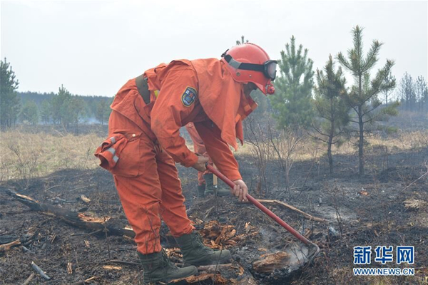 Firefighters try to cease forest fire in North China