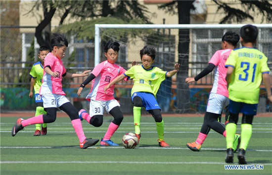 Pupils take part in football training in elementary school in Qingdao