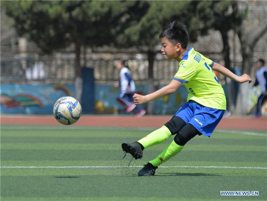 Pupils take part in football training in elementary school in Qingdao