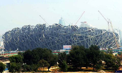 A worker cycles pass the site of the National Stadium, dubbed the 