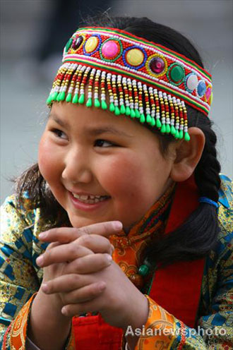 Zhong Baole, a girl of the Yugur ethnic group, smiles as she plays with other pupils at Lanzhou Qing Hua Primary School, in Lanzhou, capital of Northwest China's Gansu Province, March 15, 2008. The Beijing Organizing Committee for the Olympic Games (BOCOG) recently invited the school, which is known for having students from many ethnic groups, to submit photographs of smiling children for possible use in the August 8 Opening Ceremony of the Beijing Olympic Games. BOCOG started collecting photographs of children's smiling faces from around the world on Sept 4 last year. [Asianewsphoto] 