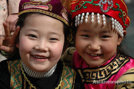 Two girls of the Hui ethnic group and wearing traditional costumes, smile for a photograph at Lanzhou Qing Hua Primary School, in Lanzhou, capital of Northwest China's Gansu Province, March 15, 2008. The Beijing Organizing Committee for the Olympic Games (BOCOG) recently invited the school, which is known for having students from many ethnic groups, to submit photographs of smiling children for possible use in the August 8 Opening Ceremony of the Beijing Olympic Games. BOCOG started collecting photographs of children's smiling faces from around the world on Sept 4 last year. [Asianewsphoto] 