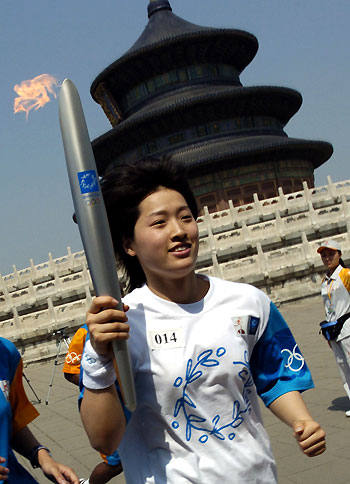 Athens swimming gold medallist Luo Xuejuan carries the torch past the Temple of Heaven in Beijing during the 2004 Olympic Torch relay in this file photo dated June 9, 2004. According to Xinhua, Luo is expected to be China's first relay runner to carry the torch following first torchbearer Alexandros Nikolaidis during the 2008 torch relay, which starts on March 24, 2008. [Xinhua]