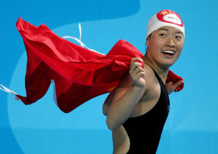 Chinese swimmer Luo Xuejuan celebrates with China's national flag after winning the women's 100m breast stroke during the Athens Games in this 2004 file photo. Xinhua cites the website of the Beijing Organizing Committee for the Olympic Games as saying Luo is expected to be China's first relay runner to carry the torch following first torchbearer Alexandros Nikolaidis during the 2008 torch relay, which starts on March 24, 2008. [Xinhua]