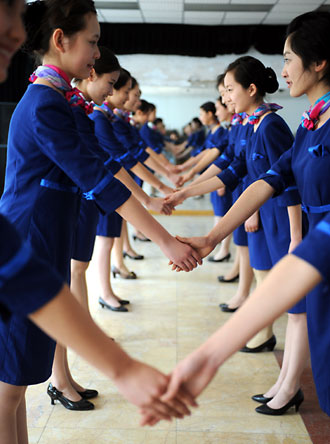 Prospective Olympic award presenters, standing in two lines and shake hands with each other during an etiquette training class in Qingdao, the eastern Chinese host city for the sailing competitions during the Olympic Games, March 24, 2008. Some 110 people, most between the ages of 16 to 18, were selected after grueling physical training to be ushers and presenters for the sailing events. [Xinhua]