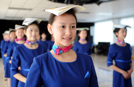 Prospective Olympic award presenters balance books on their heads during an etiquette training class in Qingdao, the eastern Chinese host city for the sailing competitions during the Olympic Games, March 24, 2008. Some 110 people, most between the ages of 16 to 18, were selected after grueling physical training to be ushers and presenters for the sailing events. [Xinhua]