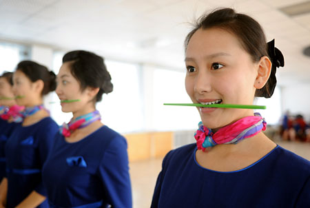 Prospective Olympic award presenters hold chopsticks in their mouths as they practice smiling during an etiquette training class in Qingdao, the eastern Chinese host city for the sailing competitions during the Olympic Games, March 24, 2008. Some 110 people, most between the ages of 16 to 18, were selected after grueling physical training to be ushers and presenters for the sailing events. [Xinhua]